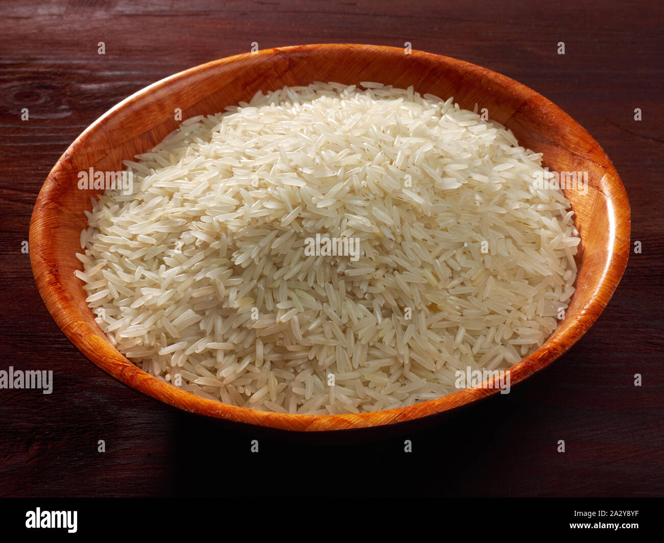 White basmati rice in a bamboo bowl on a brown background Stock Photo