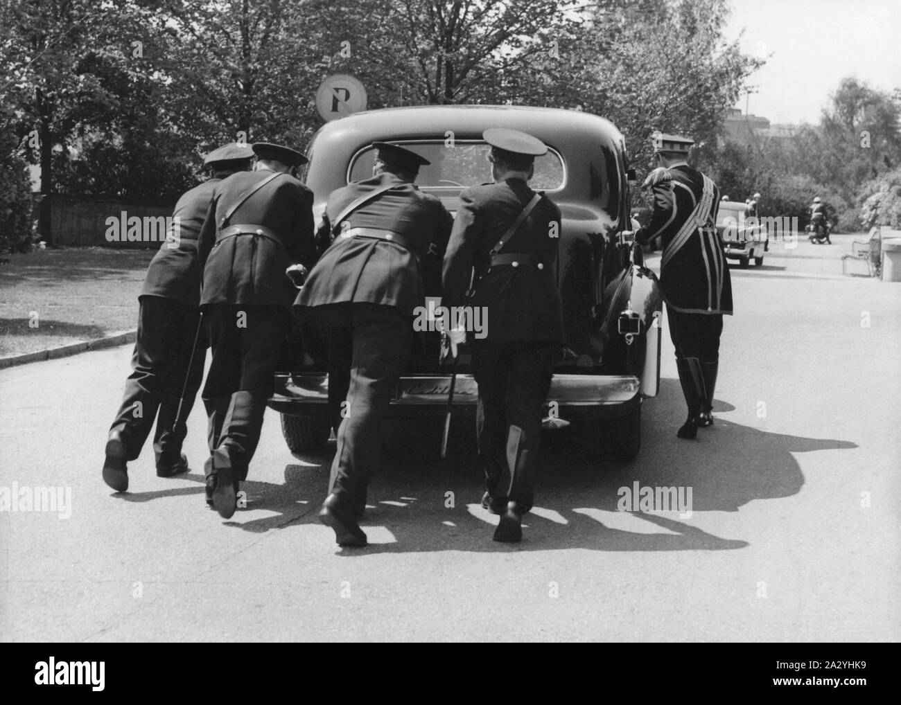 Push starting a car. Queen Elizabeth II is visiting Sweden and the car that is used when transporting the british royals has broken down. A group of men is pushing it to get it started again. Sweden June 6 1956 Stock Photo