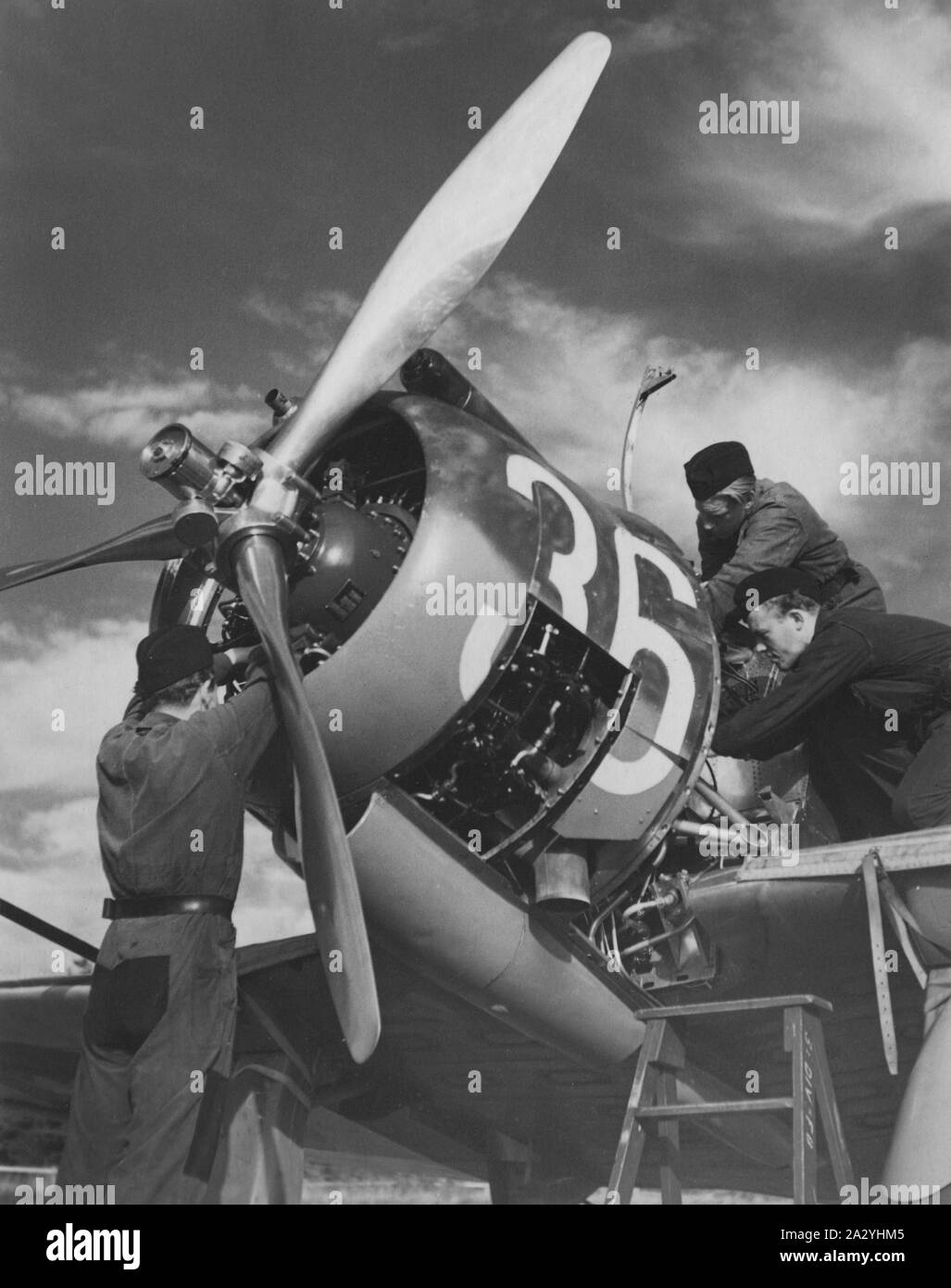 Airplane engineers.Three mechanics are performing the important last minute check of engine details before start. The airplane is a swedish single propeller engine light bomb and survaillance unit model B5. The swedish company Saab Svenska Aeroplan AB produced this airplane on license from American Northrop and their model 8A-1.  Picture taken in the 1940s during the second world war. Stock Photo