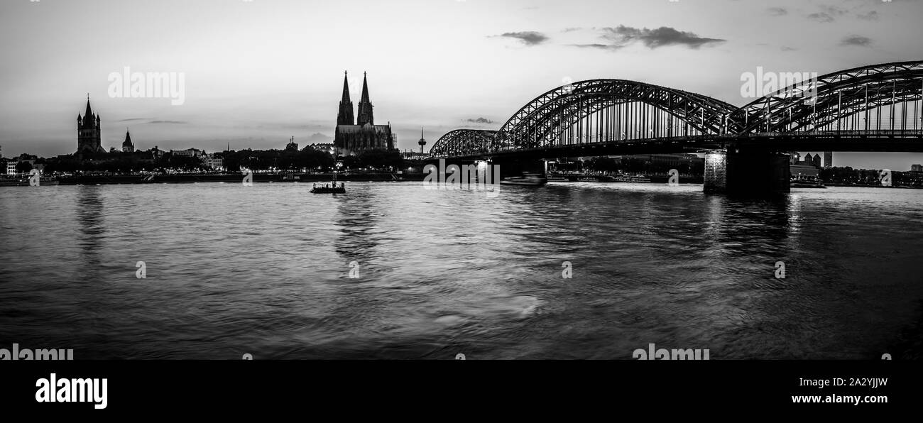 Cologne, Germany: Black and white evening silhouette skyline landscape of the gothic Cologne Cathedra, Hohenzollern railway and pedestrian bridge, the Stock Photo