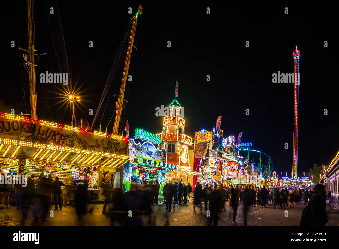 Stuttgart, Germany, October 3, 2019, Many people walking over canstatter wasen oktoberfest folk festival illuminating the night with many carousel, bi Stock Photo