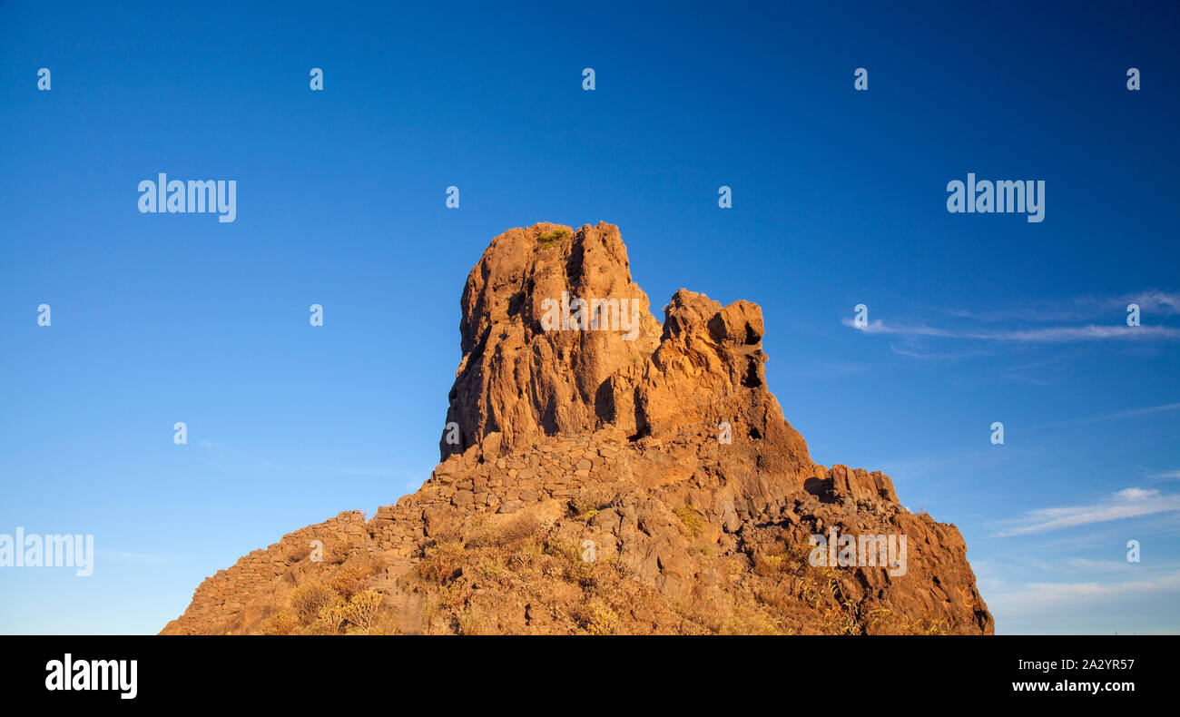 Roque Bentayga, one of the most iconic rock formation of the island of Gran Canaria, as seen from the east, morning light of autumnal equinox Stock Photo
