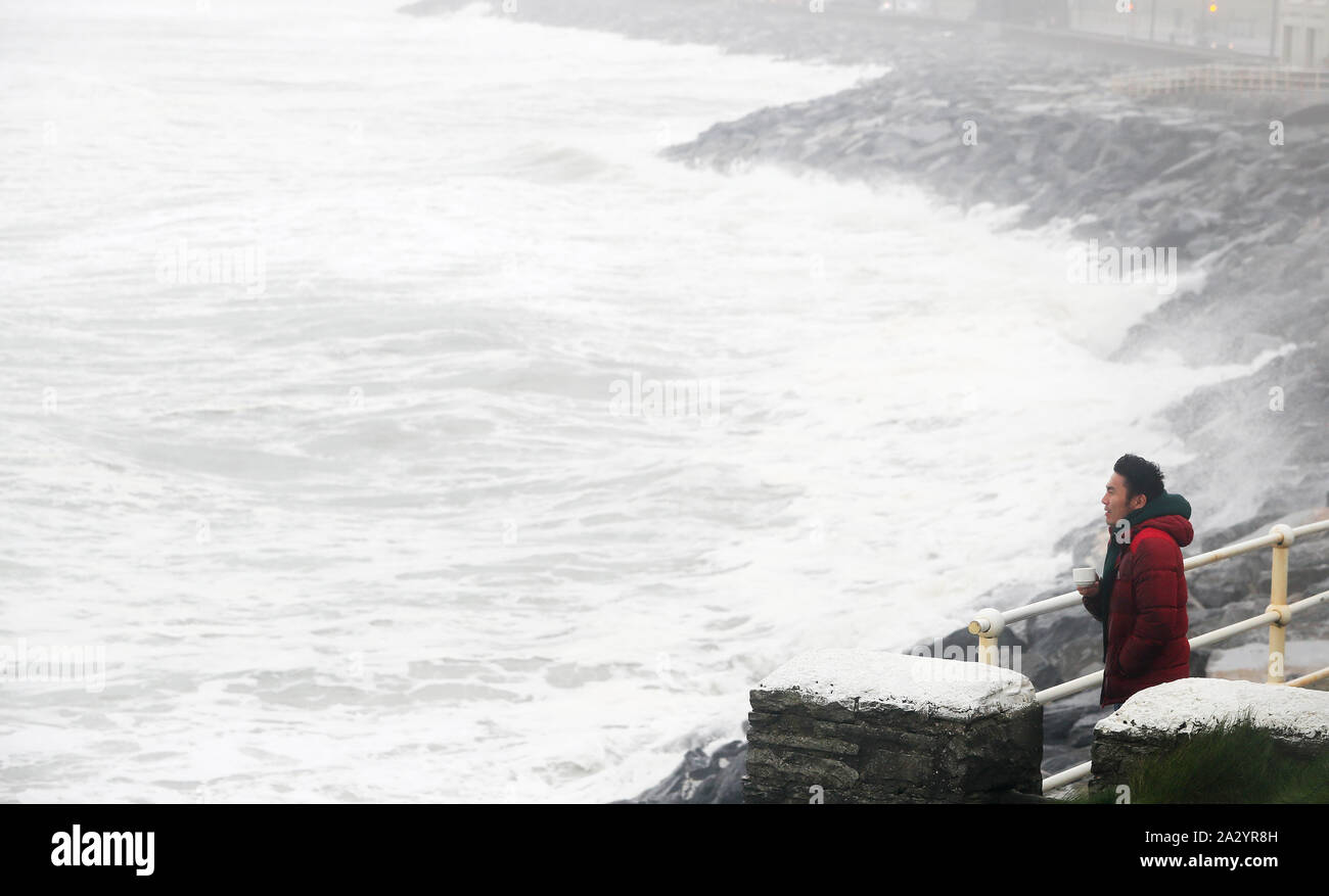 Ganaa Devee, a surfer from Mongolia, watches the waves along the sea front in Lahinch, County Clare, on the West Coast of Ireland as thousands of homes and businesses have been left without power as Storm Lorenzo passed across Ireland. Stock Photo