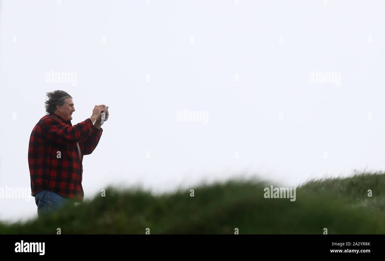 A man takes pictures from a cliff edge in Lahinch, County Clare, on the West Coast of Ireland as thousands of homes and businesses have been left without power as Storm Lorenzo passed across Ireland. Stock Photo