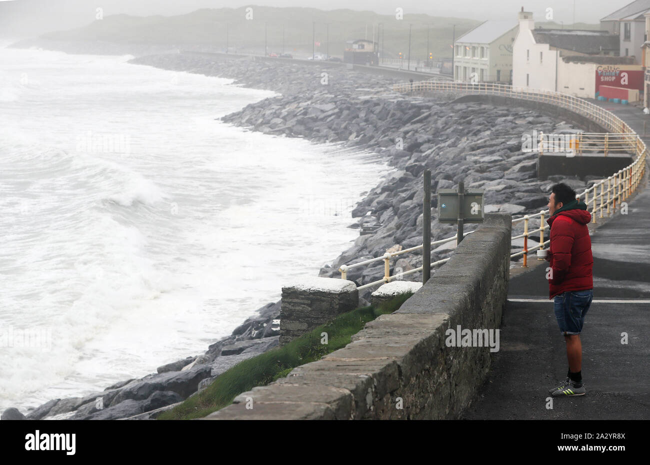 Ganaa Devee, a surfer from Mongolia, watches the waves along the sea front in Lahinch, County Clare, on the West Coast of Ireland as thousands of homes and businesses have been left without power as Storm Lorenzo passed across Ireland. Stock Photo