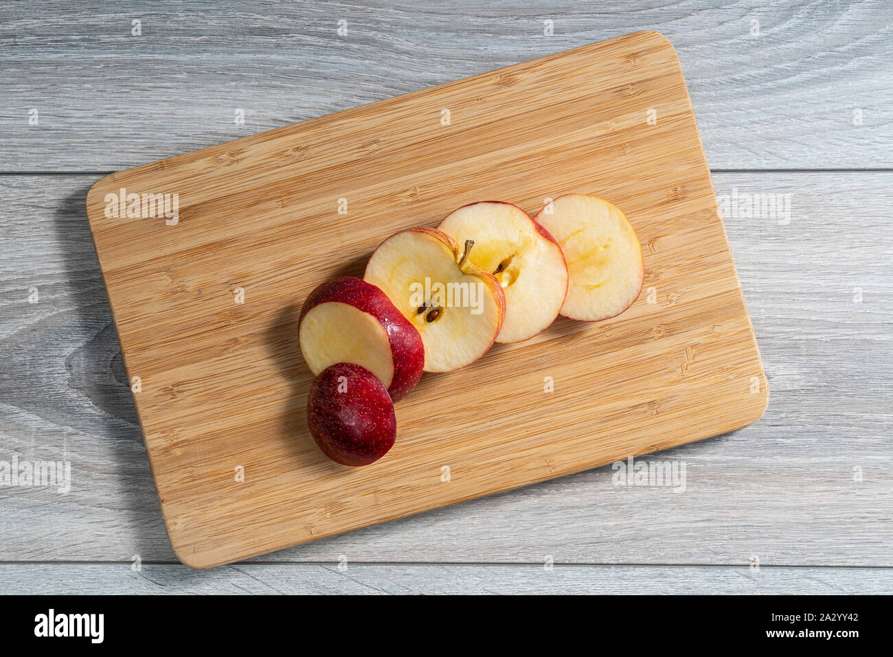 a red apple sliced on a wooden board Stock Photo