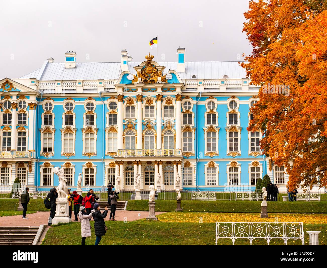 Tsar’s Village (Pushkin), Russia, 4th October 2019. Autumn colours at the Summer Palace of the Russian Tsars. Beautiful orange and gold colours of the trees around Catherine Palace and Catherine Park garden with Asian tourists taking photographs Stock Photo