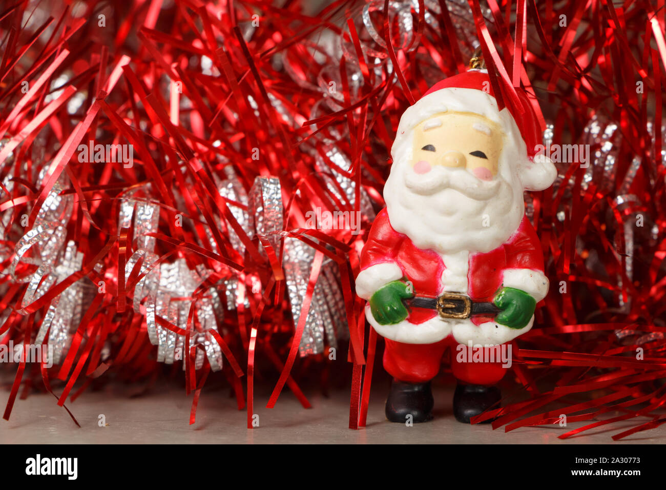 Santa Claus figurine and red and silver tinsel as decoration for Christmas Stock Photo