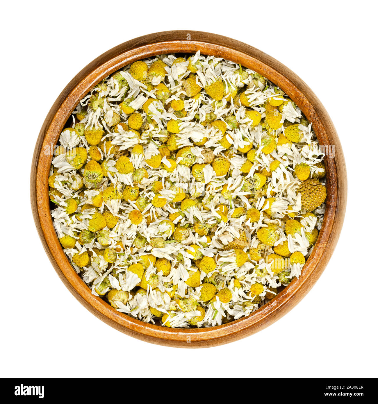 Dried chamomile blossoms in wooden bowl. Camomile tea, flowers of Matricaria chamomilla, used for herbal infusions and in traditional medicine. Stock Photo