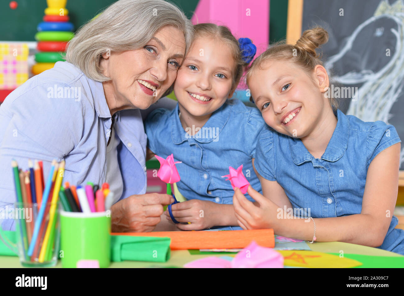 Senior woman with tweenie girls drawing at home Stock Photo