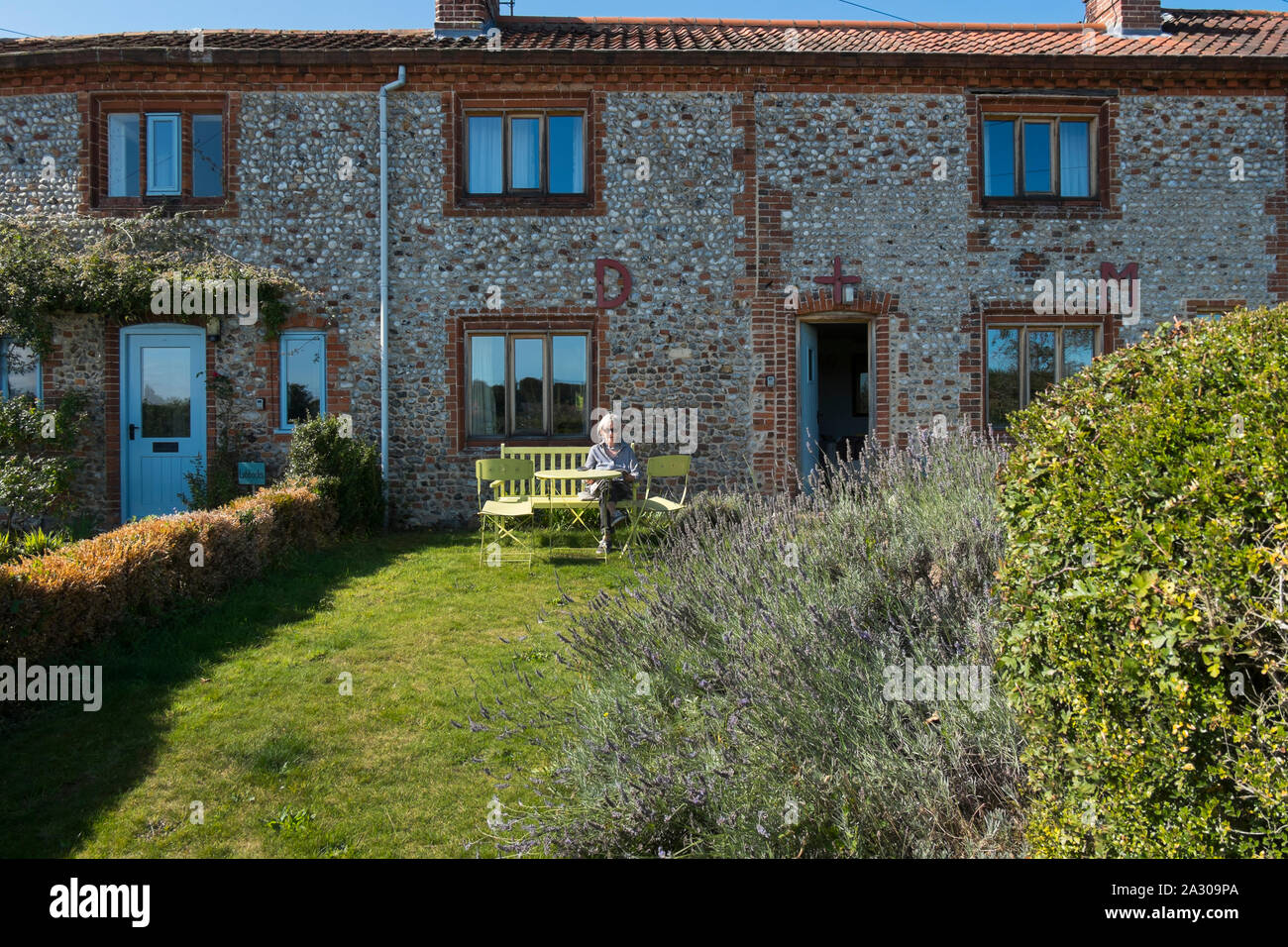 Grey haired grandmother sitting on a bench reading a magazine outside