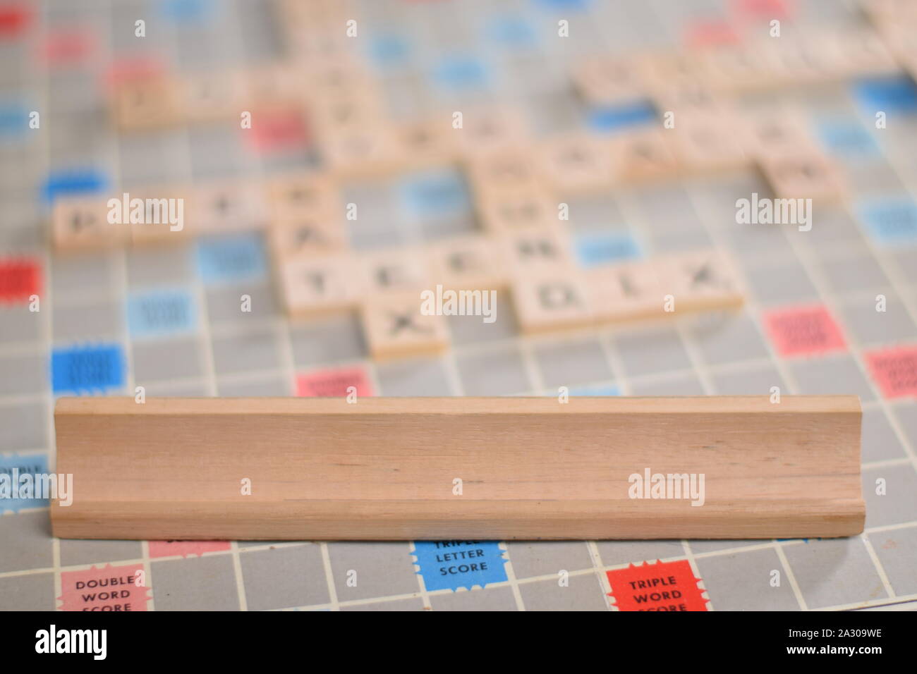 0 blank wooden scrabble tiles on a tile-rack, for you to fill in your own word. In the background a vintage board, out of focus, with copy space Stock Photo