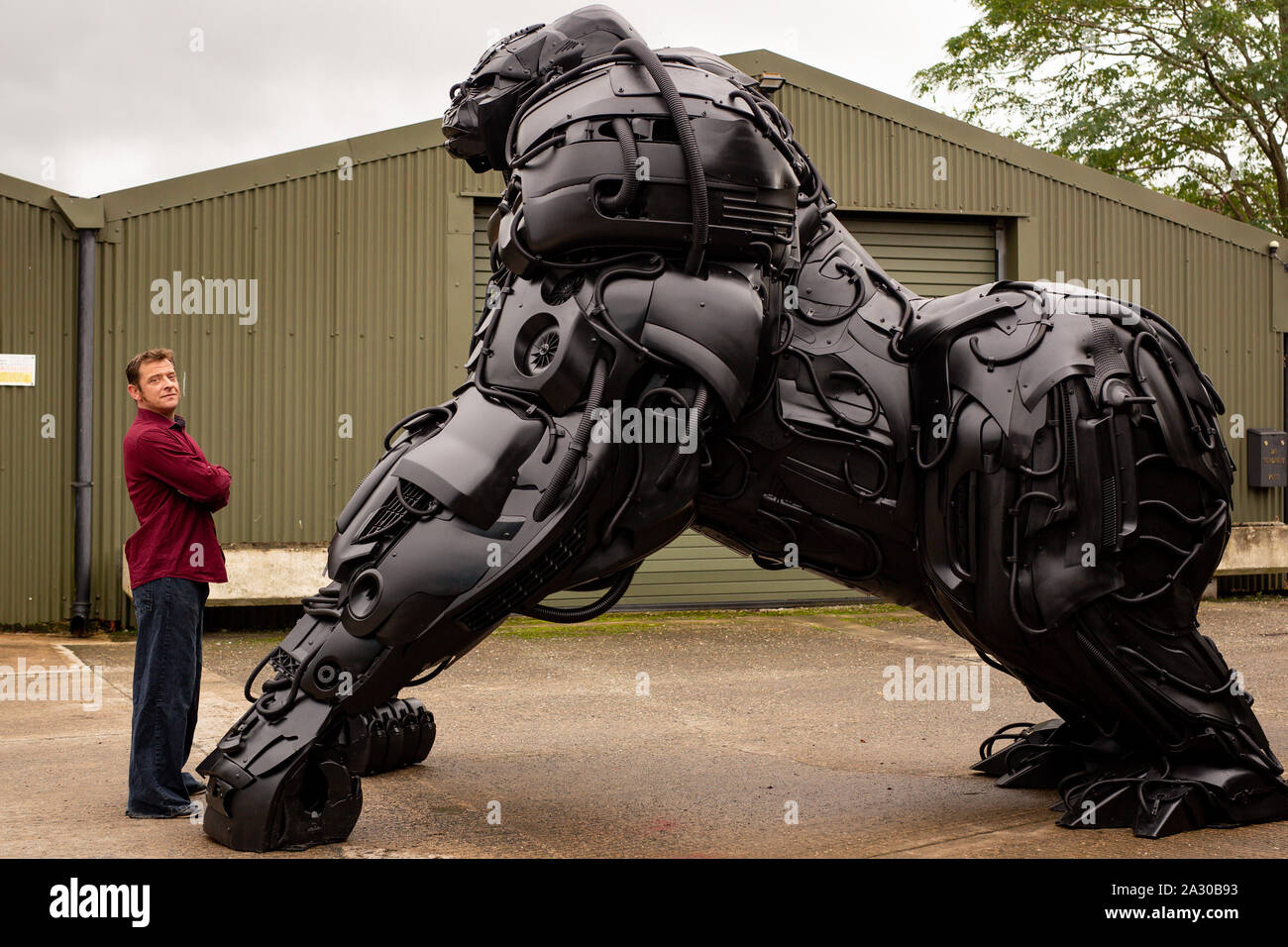 Sculptor Luke Kite with his 12ft sculpture of a gorilla, entitled 'Gorilla Apocalypse', created entirely from scrap car bumpers and panels discarded from only the last decade, on display at the British Ironwork Centre in Oswestry, Shropshire. Stock Photo