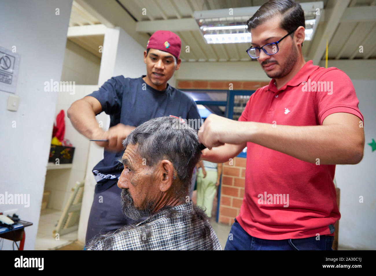 Venezuela Valencia Members of the Reformed church hairdressing by Wuanliz Ortega (24) and Kevin Duran (30) cutting Hector Lopez(70) 05-07-2019 foto Ja Stock Photo