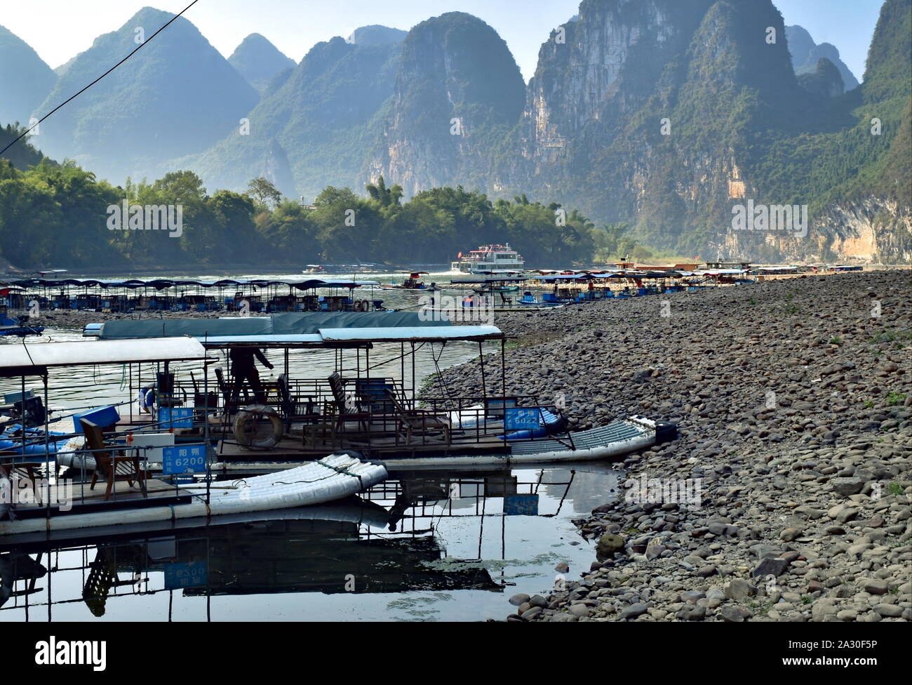 Li river basin bamboo raft boats docked by shore and dramatic mountains near Guilin, China Stock Photo