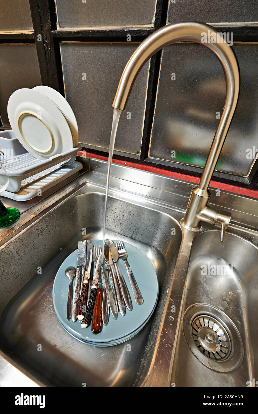 Dirty plates and cutlery in kitchen sink before washing Stock Photo - Alamy