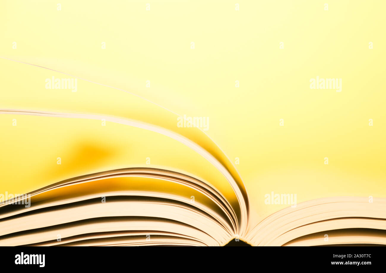Book pages turning over yellow background. Pages flipping over.  Stock Photo