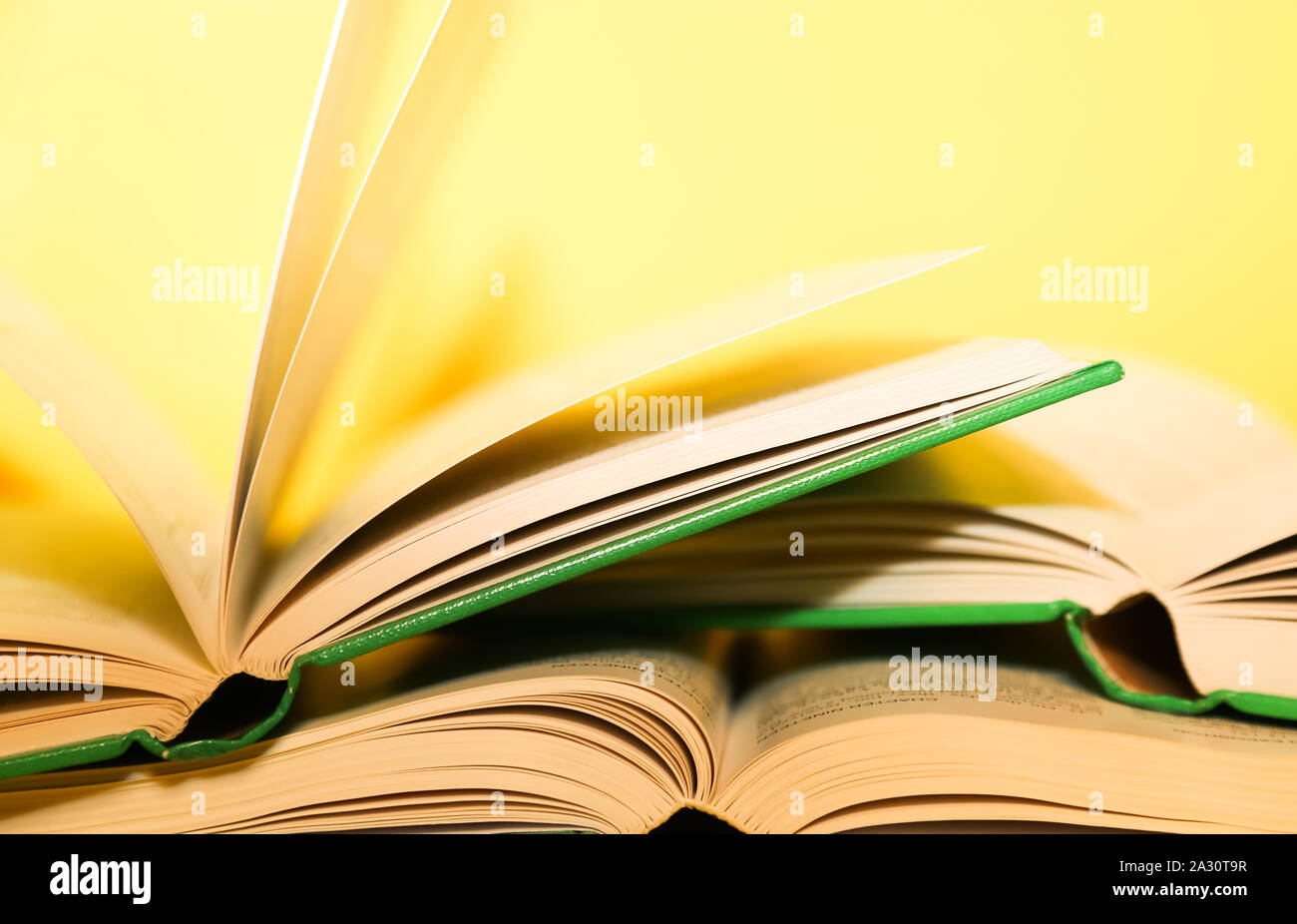 Yellow book stack, book pages turning, over a yellow background Stock Photo Alamy