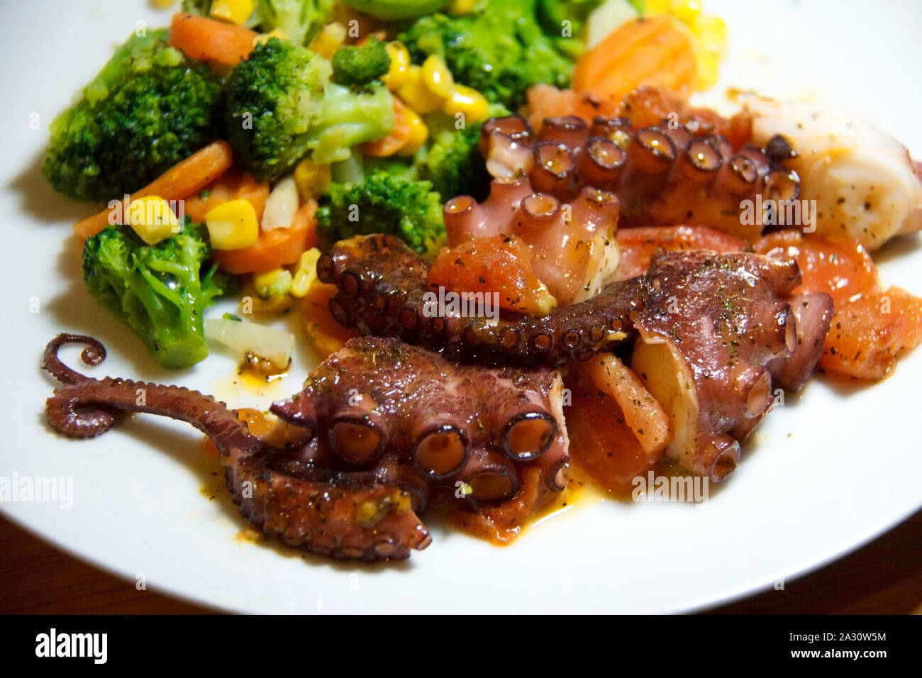 Ready to eat octopus with vegetables on a plate Stock Photo