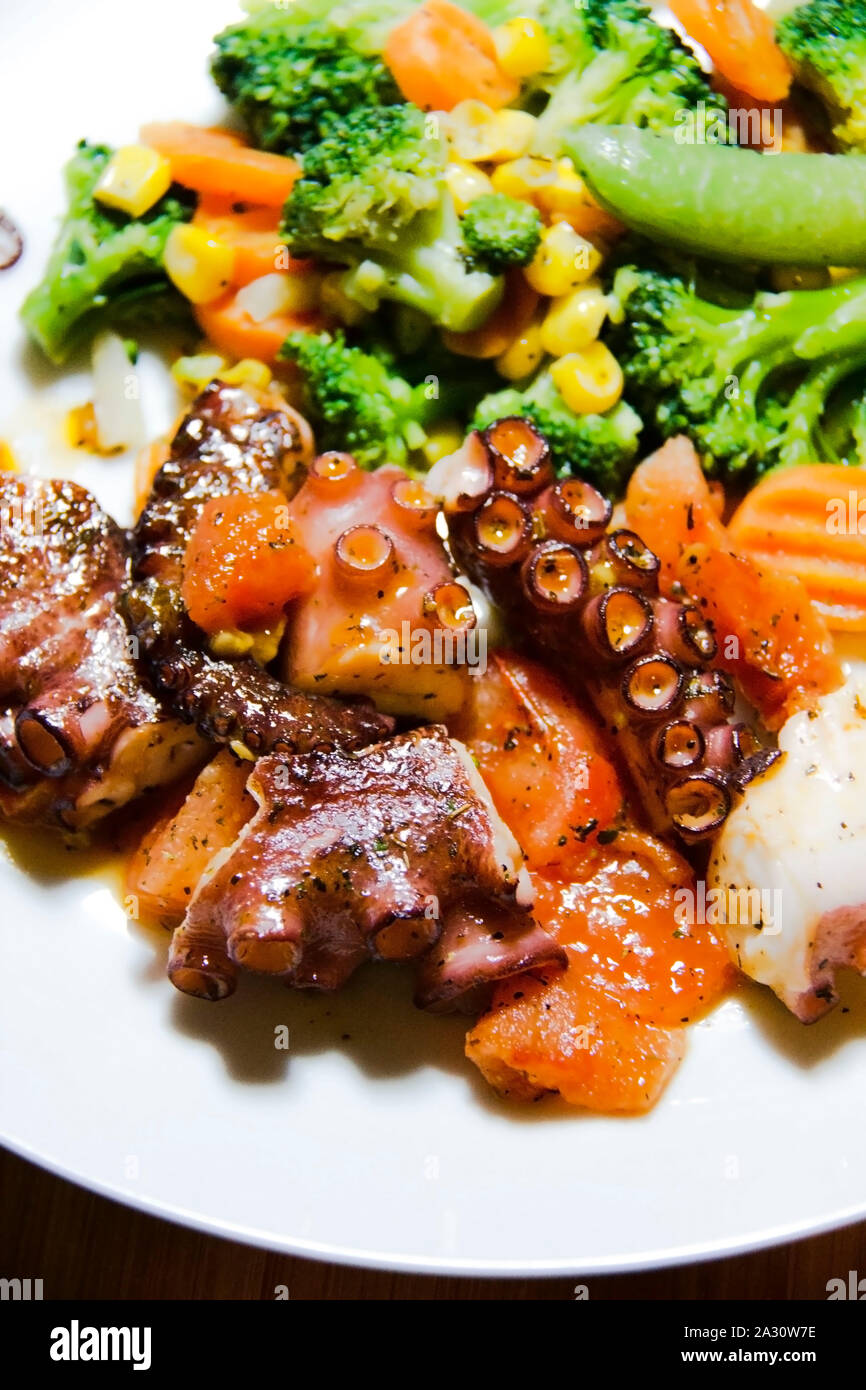 Ready to eat octopus with vegetables on a plate Stock Photo