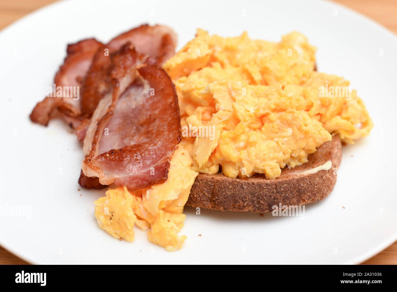 Bacon and scrambled egg with slice of toast on a white plate Stock ...