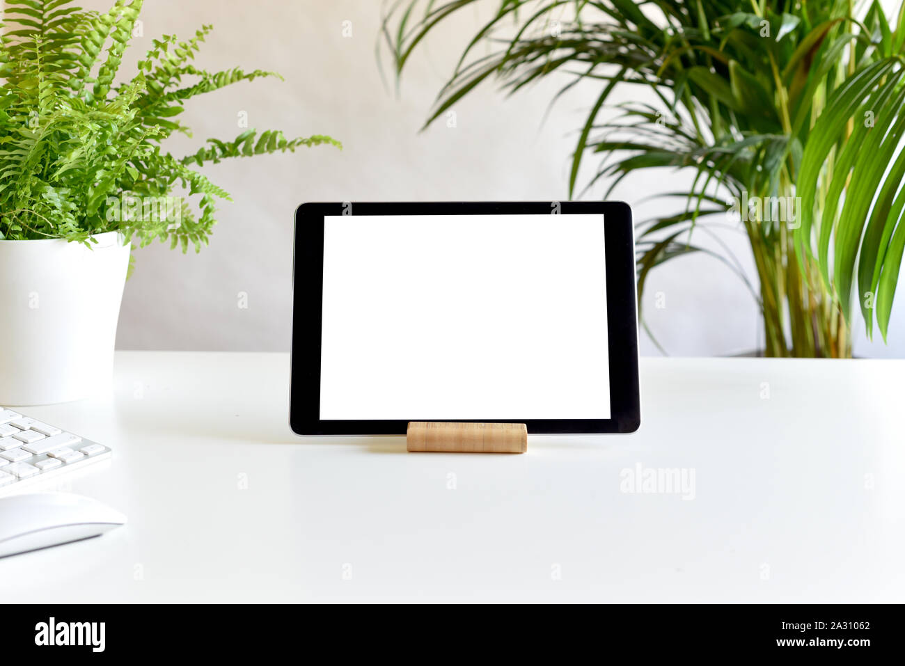 Blank white screen on portable tablet device on modern office desk Stock Photo