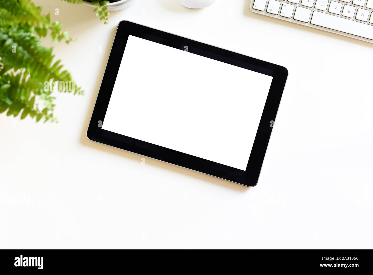 Blank white screen on portable tablet device on modern office desk
