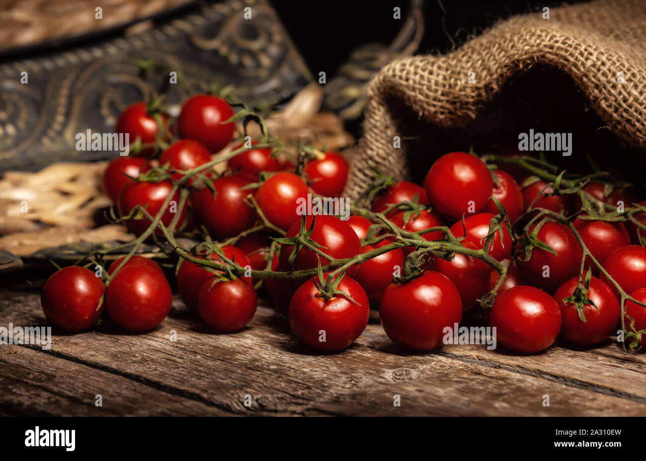 Still life of cherry tomatoes on wooden rustic table with jute sack. Stock Photo