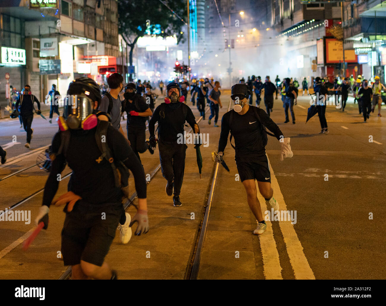 Hong Kong. 4 October 2019. Violent scenes in Hong Kong tonight with pro-democracy protestors vandalising shops and setting fire to the entrances of MTR stations. Protestors are angry with Chief Executive Carrie Lam's use of Emergency Powers to ban the wearing of masks during protests. Further demonstrations planned over the weekend. Pic; Protestors retreat from police charge and teargas attack in Causeway Bay. Iain Masterton/Alamy Live News. Credit: Iain Masterton/Alamy Live News Stock Photo