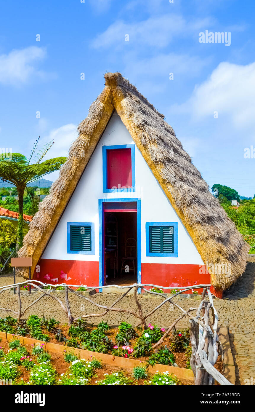 Old traditional house in Santana, Madeira Island, Portugal. Wooden, small, triangular and colorful houses represent a part of Madeira heritage. Small front garden. Historical building, tourist place. Stock Photo