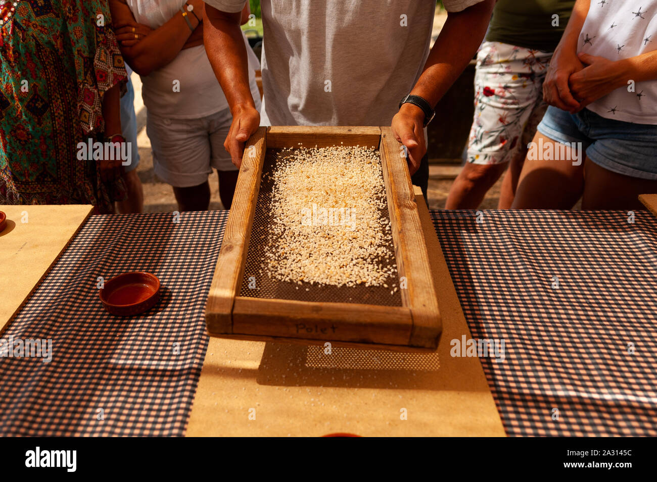 farmer filtering rice grains with old traditional strainer on table