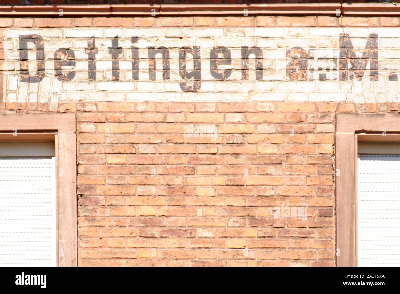 The name tag of the city Dettingen at the brick facade of an old building. Stock Photo