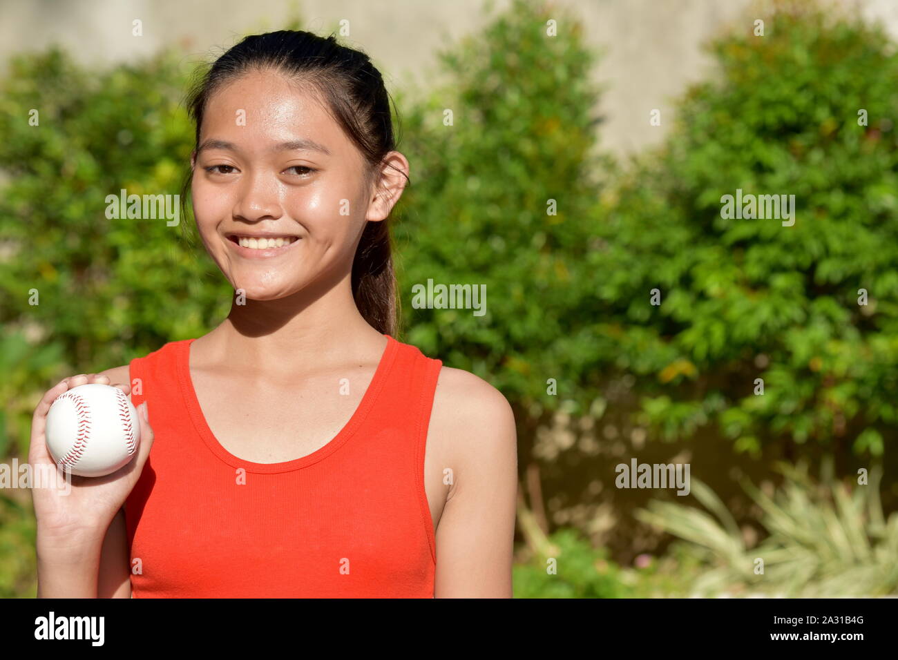 Smiling Minority Female Baseball Player With Baseball Stock Photo