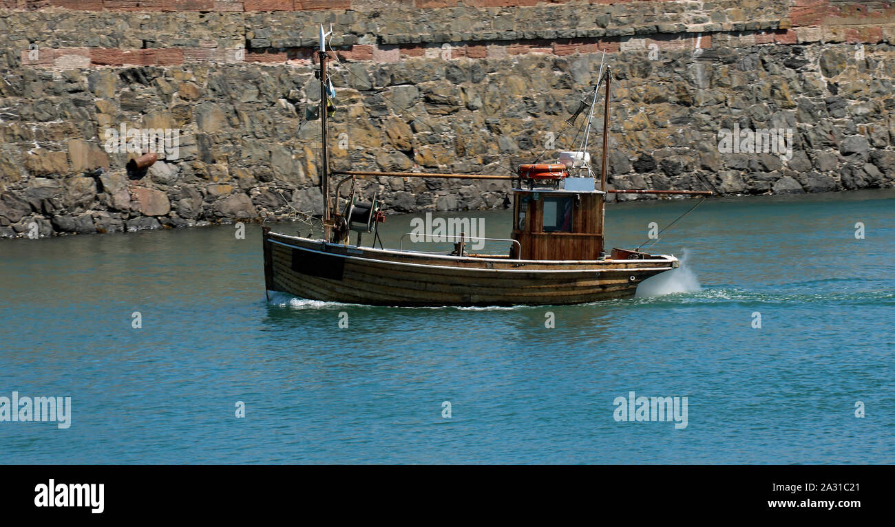 Small fishing boat entering a coastal harbour Stock Photo - Alamy