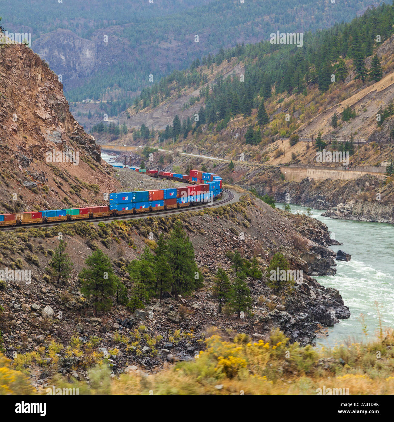 Canadian National freight train carrying colourful containers to Vancouver through the Thompson River valley in British Columbia seen from the Rocky M Stock Photo