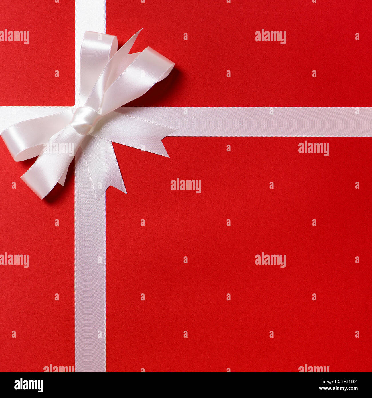 White ribbon bow, red gift wrap paper background, copy space, vertical