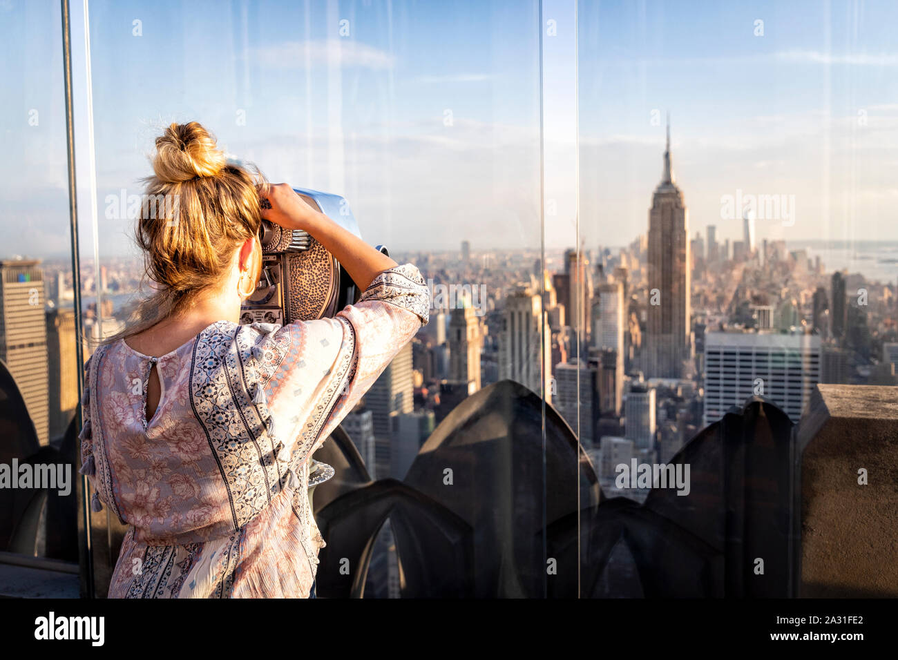 e of the iconic telescopes on Top of the Rock Observatory with the Empire State Building in the distance, New York City, USA. Stock Photo