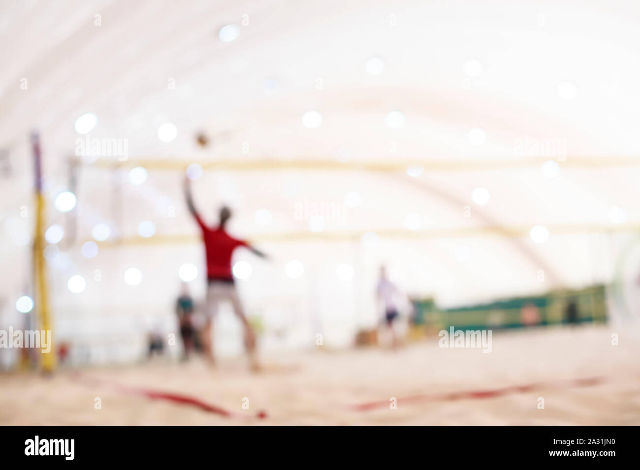 Blurred silhouettes of people playing beach volleyball in the inflatable hangar winter. Stock Photo