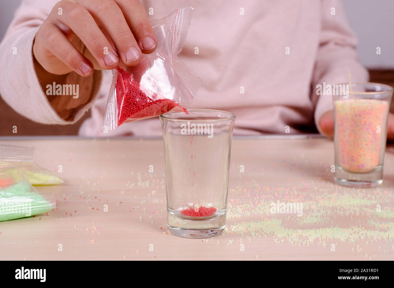 Making candles by yourself process. Little girl making candle in the glass from soy wax parsley