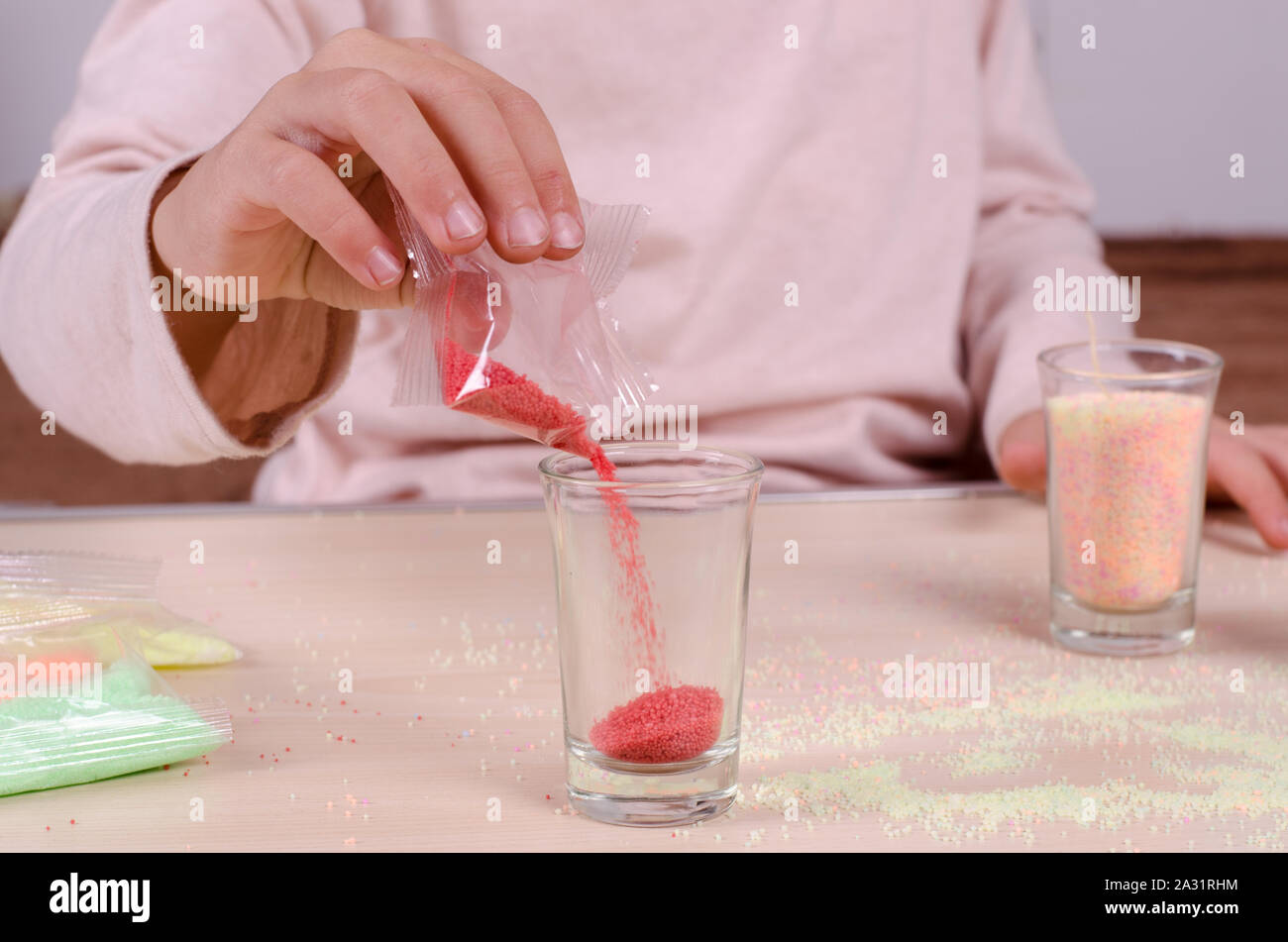 Making candles by yourself process. Little girl making candle in the glass from soy wax parsley