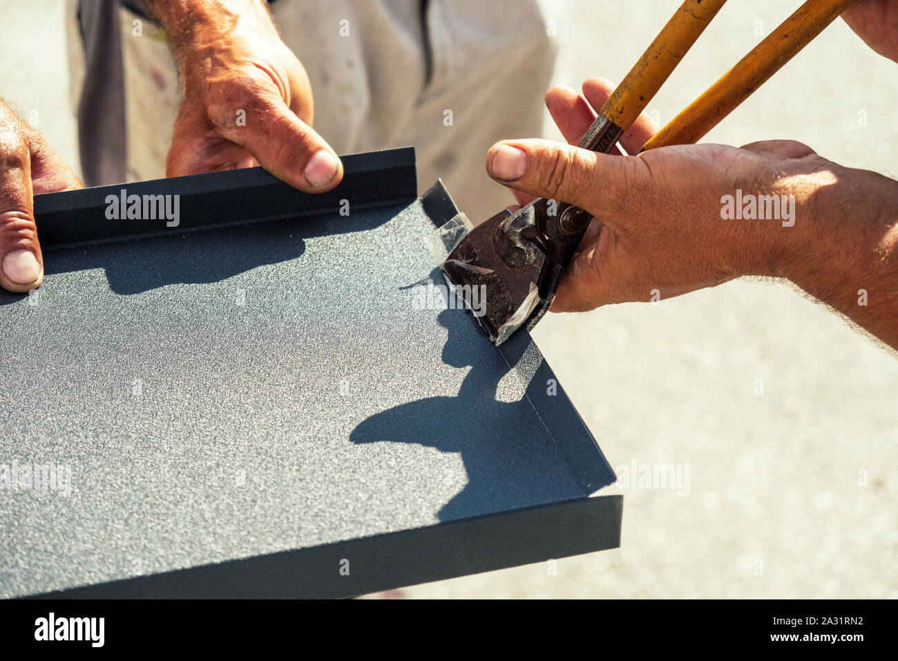 Worker bending the sheet metal flashing with tinsmith tool Stock Photo