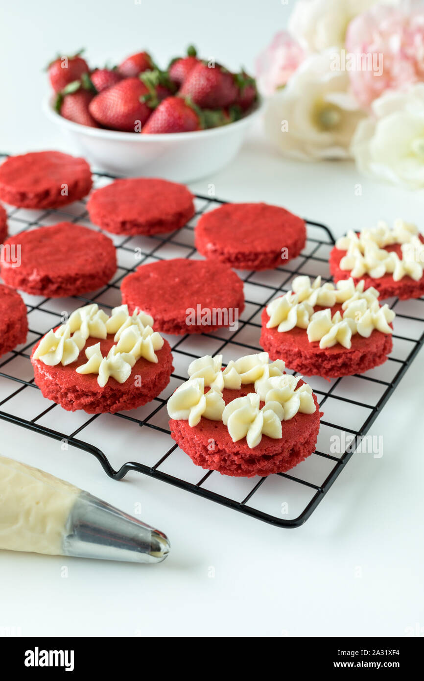 Miniature Red Velvet Cakes with cream cheese frosting and fresh strawberry topping on a cooling rack Stock Photo