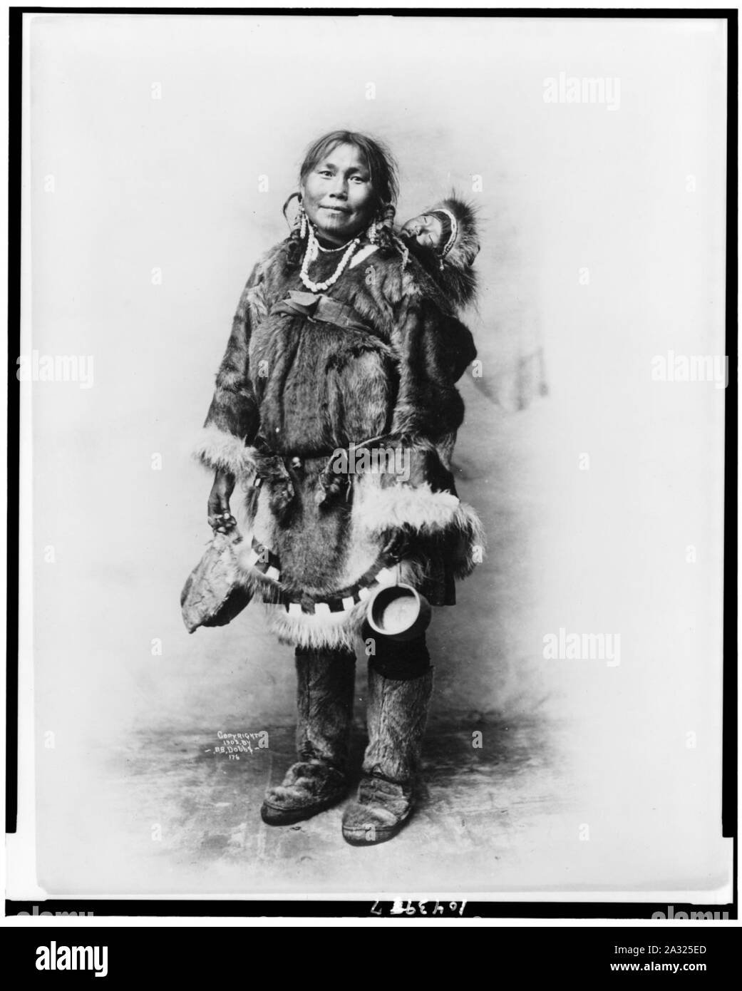 Eskimo mother dressed in fur clothing with baby on her back Stock Photo