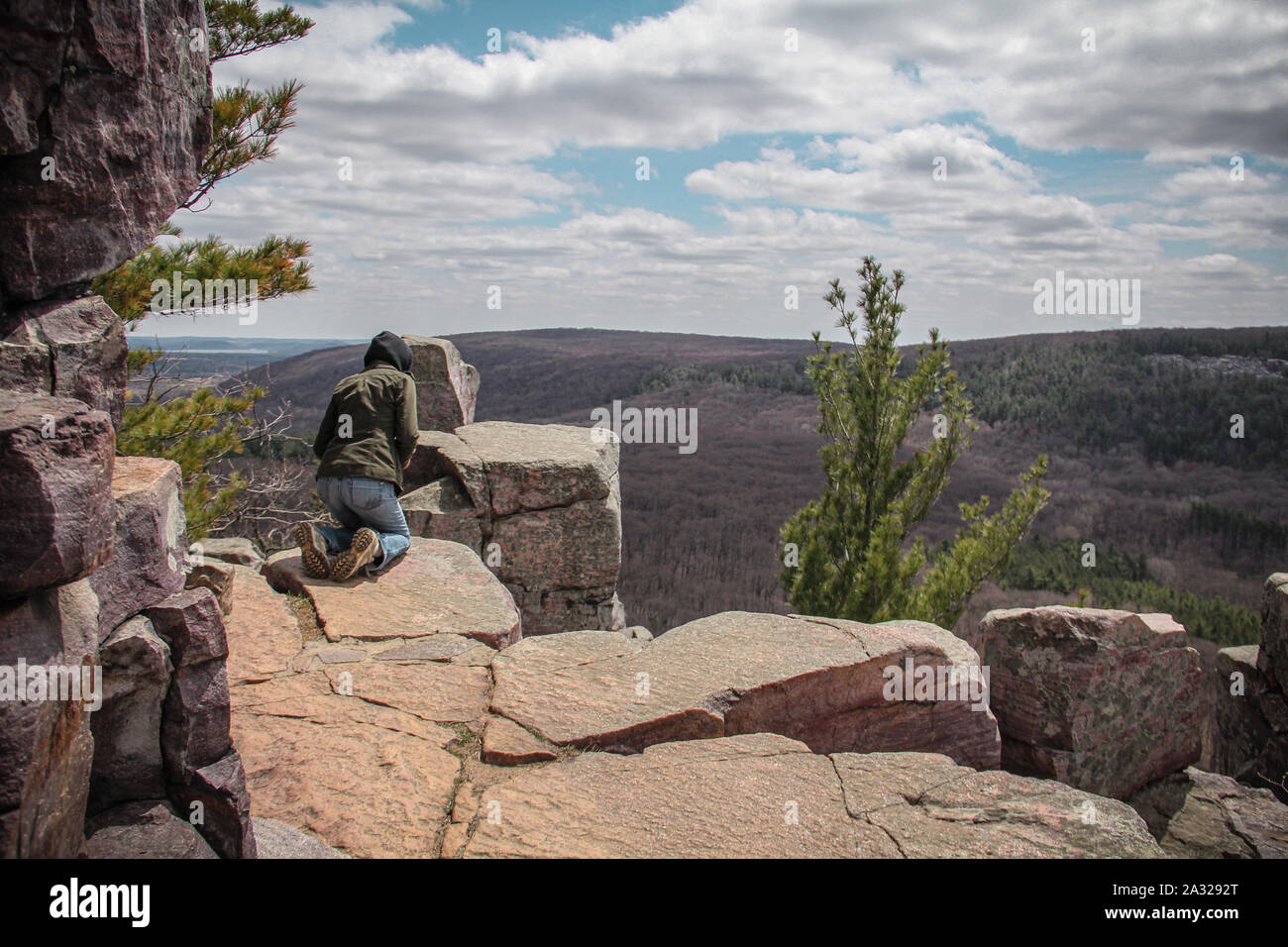 Woman hiking and looking over the edge of a cliff at Devil's Lake State Park Stock Photo