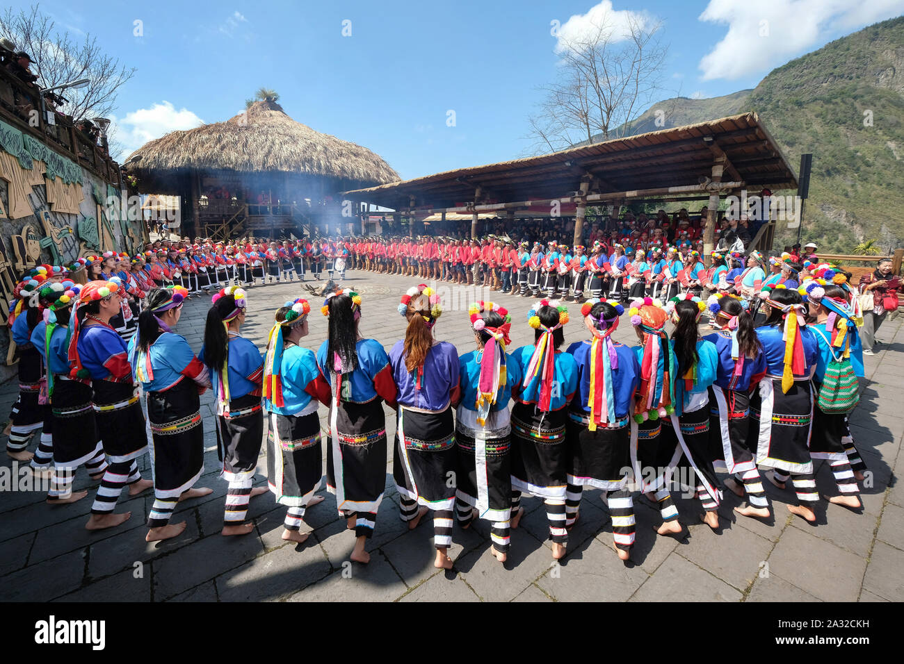 Song and dance celebration of the red and blue-robed Tsou tribe at the Tsou Mayasvi festival around the Cuba, the tribe's meeting house in the village of Tefuye in the Alishan Mountains. Main ceremony, all members of the tribe, hand-in-hand and led by the elders, dance and sing songs in praise of the God of War, and chant the heroic deeds of their ancestors. near city of Chiayi, Taiwan, Asia Stock Photo