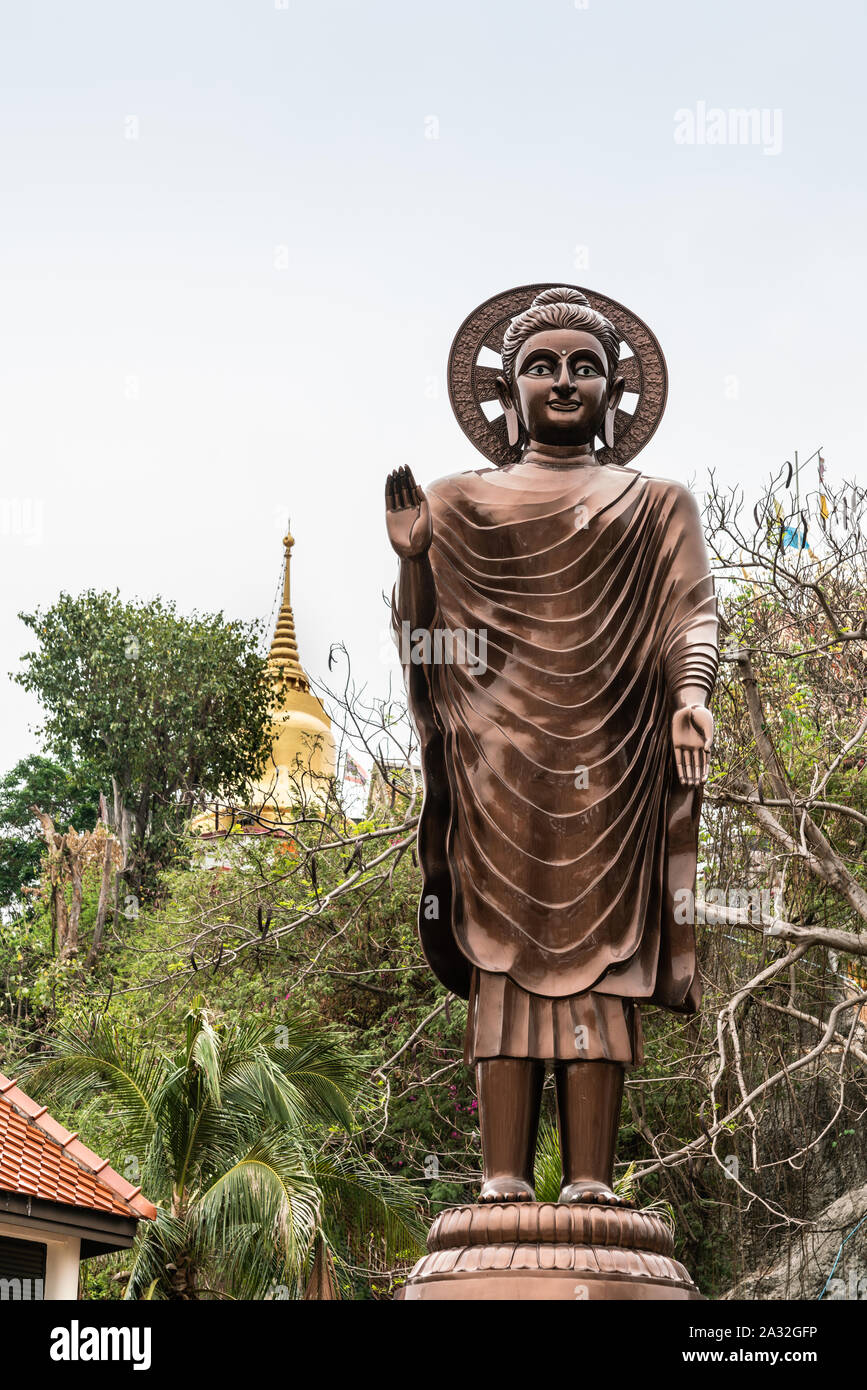 Si Racha, Thailand - March 16, 2019: Closeup of Giant bronze statue of enlightened, compassionate bodhisattva with halo on Ko Loi Island under silver Stock Photo