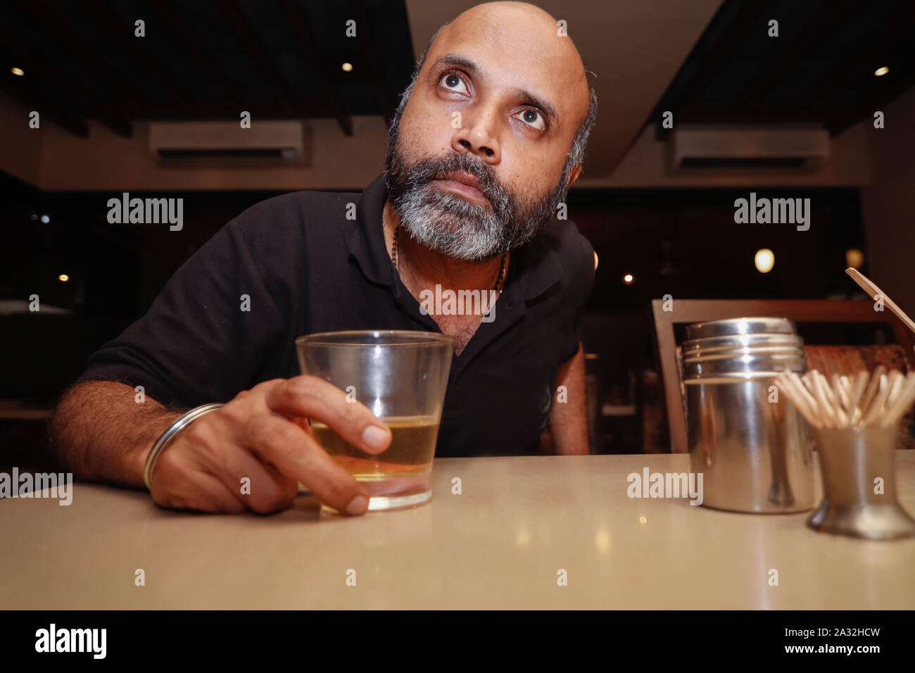 A model posing as a drunk man in deep thoughts looking up Stock Photo