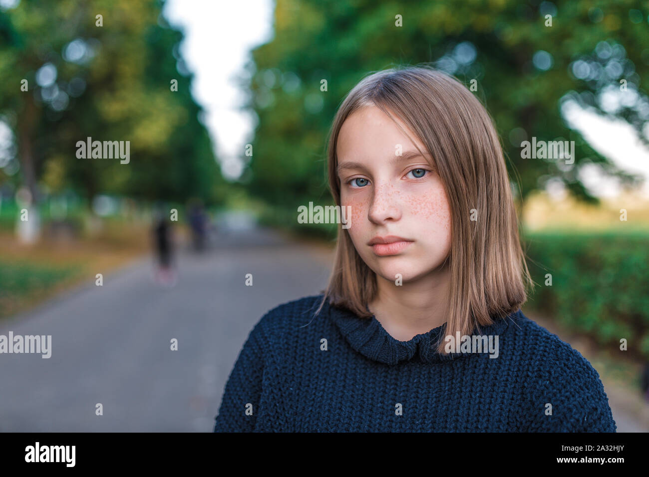 Portrait of teenager girl 12-15 years old, in summer in park, autumn day. Free space, resting after school lessons, on street. In sweater, close-up Stock Photo