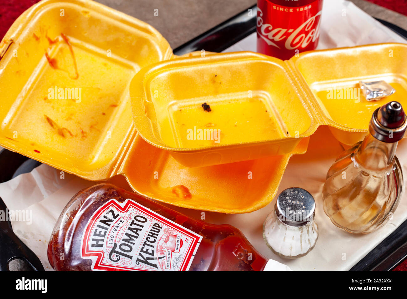 WELWYN GARDEN CITY, UK - OCTOBER 01, 2019: Empty take away cartons on a tray with a drink can and a ketchup bottle Stock Photo