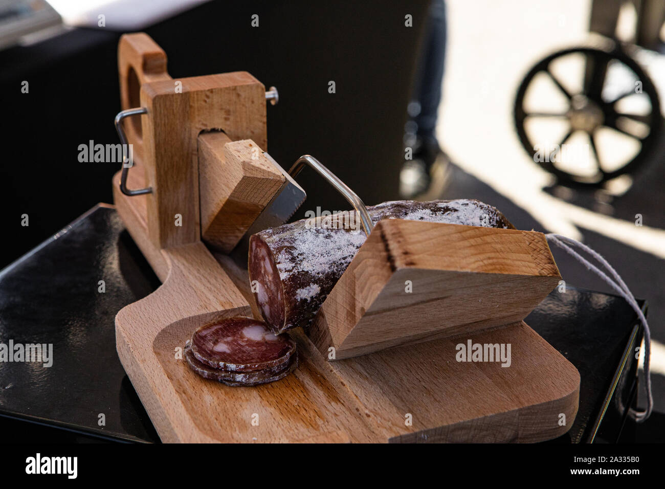 A traditional wooden salami slicer is seen close up on a market stall